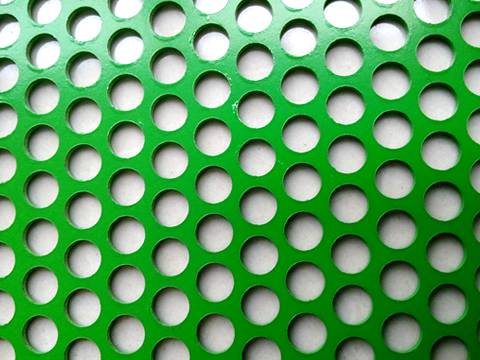 Grünes Pulver, das ringsum perforiertes Blatt des Lochs beschichtet